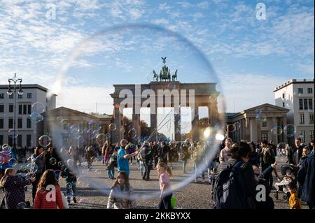 12.11.2022, Berlin, Germany, Europe - Street performer / busker is seen blowing soap bubbles with loops in a string at the Paris Square, Pariser Platz. Stock Photo