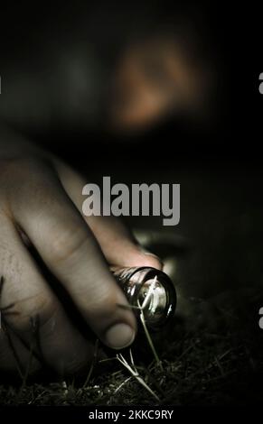 Focus On The Hand Of A Unconscious Drunk Man Passed Out In A Field At Night From An Addiction To Alcohol Stock Photo