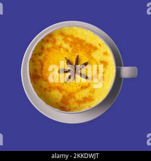 Flay lay Ayurvedic golden turmeric latte milk tea made with turmeric and other spices on blue background. Healthy medicine drink. Stock Photo