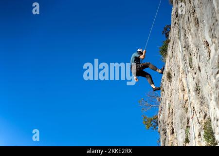 Man is climbing on the rocks in the mountians. Stock Photo
