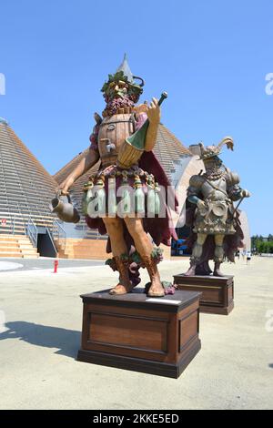 Statue of the character Enolo with glass bottles, wooden barrel, demijohn and jar standing in a group of statues of The Food People at Expo Milan 2015 Stock Photo