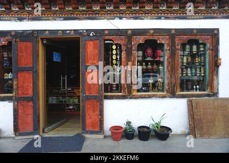 Typical shop front with traditional painted woodwork on the street in Thimphu, Bhutan. Through the window you can see colorful prayer wheels and more. Stock Photo