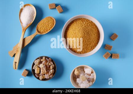Different types of sugar -crystal sugar caramel , brown demerara, white on a blue background, top view. Stock Photo