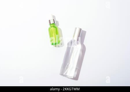 Cosmetic bottles with serum and tonic on white background, sharp shadows. Natural cosmetics concept. Top view, flat lay. Stock Photo