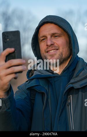 Hiker in cold weather taking photos with his smart phone Stock Photo