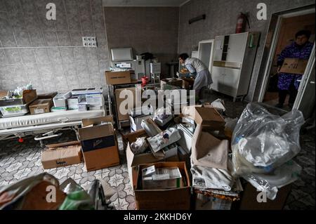 VILNIANSK, UKRAINE - NOVEMBER 23, 2022 - Healthcare worker salvage equipment and documents after a missile attack by Russian troops destroyed the mate Stock Photo