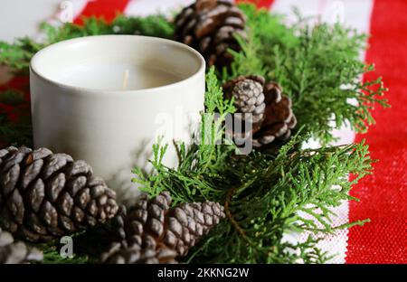 christmas composition with a candle, pine cones and green needles with red table runner  Stock Photo