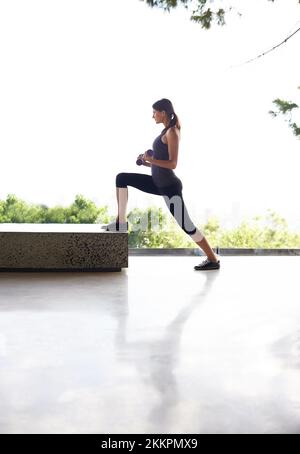 And step...an attractive young woman working out in a studio with a view. Stock Photo