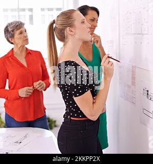 Put on your thinking caps, ladies. a group of female architects working together on a project. Stock Photo
