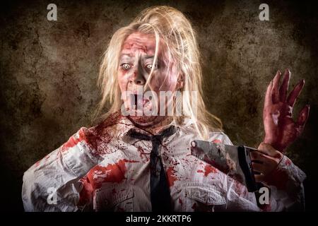 Halloween gore photo of a dead female zombie with bloody saw and amputated hand. Slasher concept Stock Photo