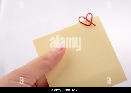 Hand holding a notepaper heart shaped clip on a white background Stock Photo