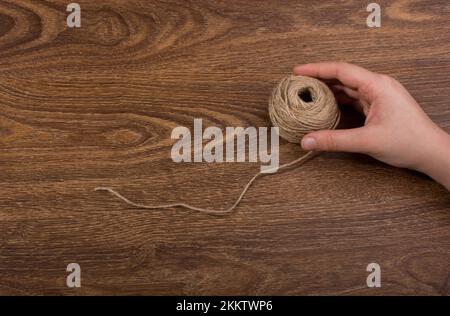 Spool of brown string in hand on brown background Stock Photo - Alamy