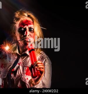 Evil female halloween zombie with bloody face holding bomb on creepy dark background. Attack of the dead Stock Photo
