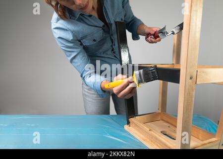 Young women preparing to restore a stepladder for children as a hobby house improvement. On a covered table. Painting with brush Stock Photo