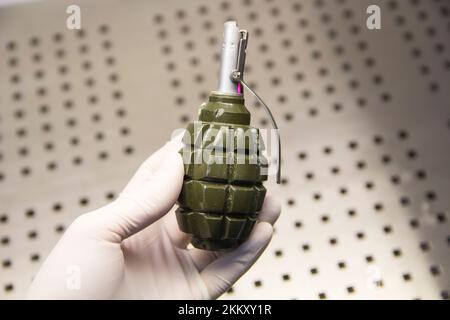 A hand in a rubber glove holds a grenade close-up Stock Photo
