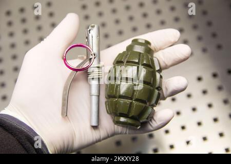 A disassembled grenade lies on a hand in a rubber glove Stock Photo
