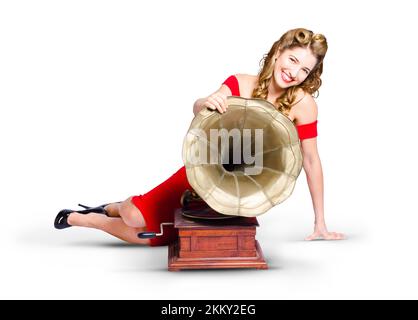 Vintage style portrait of a beautiful retro pin-up girl in red dress posing next to analogue record phonograph on white background Stock Photo