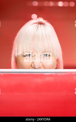 An Irate Female Worker Peers Over An Office Partition Into The Neighbouring Cubicle In A Fit Of Red Rage Stock Photo
