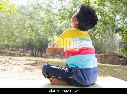 back view Young Boy doing yoga with hands in prayer position at outdoor Stock Photo