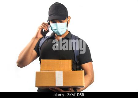 happy indian delivery man talking on smartphone and parcel box in black uniform Stock Photo