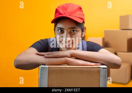 Delivery Woman Lying On Parcel Box and looking at camera Stock Photo