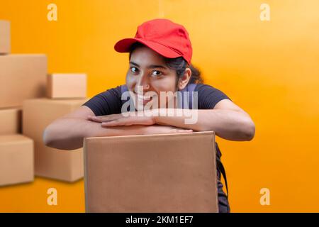 Delivery Woman Lying On Parcel Box and looking at camera Stock Photo