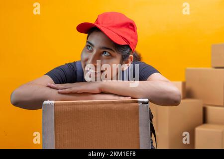 Smiling Delivery Woman Lying On Parcel Box and looking elsewhere Stock Photo