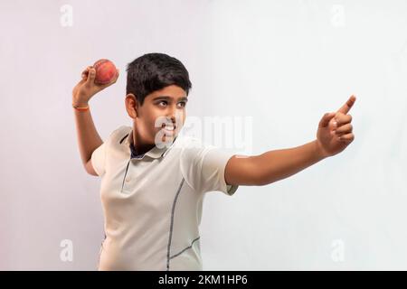 A boy in cricket uniform standing Holding a ball Stock Photo