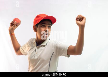 A boy in cricket uniform standing Holding a ball Stock Photo