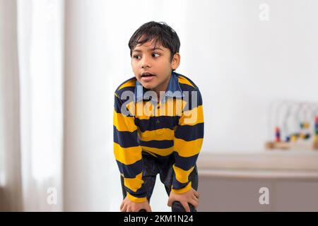 An Indian boy bending forward and looking Away Stock Photo