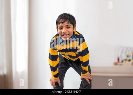 An Indian boy bending forward and looking At Camera Stock Photo