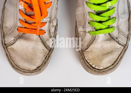 worn old torn white sneakers with colored laces on a white background Stock Photo