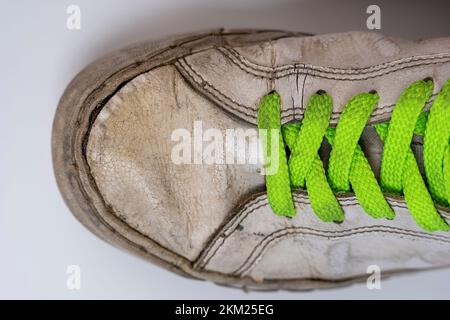worn old torn white sneakers with colored laces on a white background Stock Photo