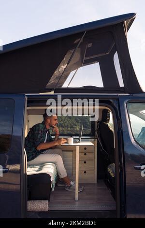 man in his camper van working on his laptop Stock Photo