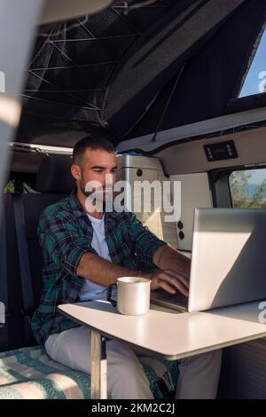 man working on his laptop from his camper van Stock Photo