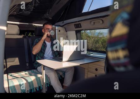 man working on his laptop from his camper van Stock Photo
