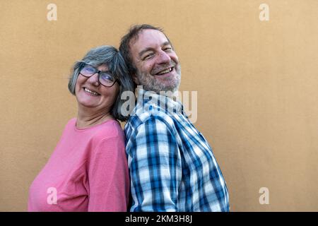 married elderly couple back to back, portrait of happy retired people, copy space Stock Photo