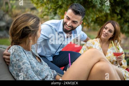 group of young adult people having fun at poolside party, handsome man smiling at charming woman, millennials people chatting and flirting Stock Photo