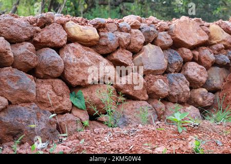 fence wall constructed from large red stones and forming beautiful texture as background Stock Photo