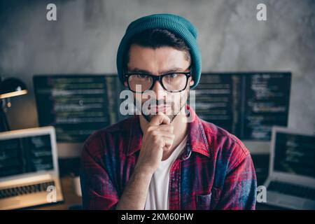 Photo of ponder pensive freelancer wear hat glasses arm hand chin thinking new project indoors workplace workstation loft Stock Photo