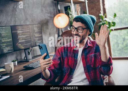 Photo of positive excited freelancer wear hat glasses having video call modern gadget indoors workplace workstation loft Stock Photo