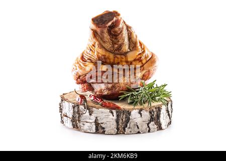 Smoked pork Bavarian knee with rosemary and chili peppers on birch wood - isolated on white. Stock Photo