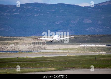 A small single-engine plane taking off from Ushuaia, Argentina.  With mountains in the background. Stock Photo