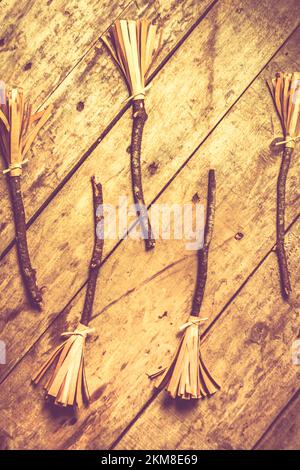 Halloween themed still life photo of home made witches broomsticks on wooden background. Witchcraft and sourcery Stock Photo