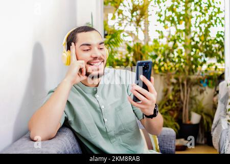 A closeup of a happy, relaxed man at home using a phone sitting on the sofa Stock Photo