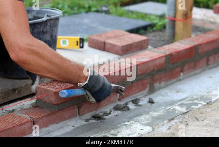 Construction work in progress. Male builder working with red bricks. Masonry wall close up photo. Stock Photo