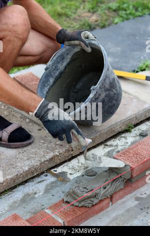 Construction work in progress. Male builder working with red bricks. Masonry wall close up photo. Stock Photo