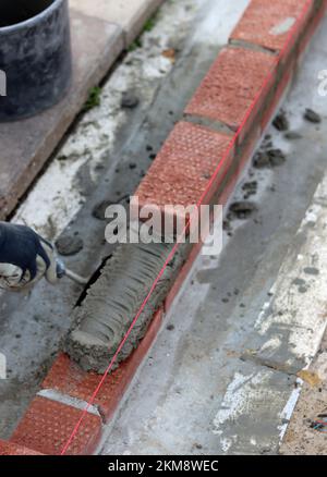 Construction work in progress. Male builder working with red bricks. Masonry wall close up photo. Stock Photo
