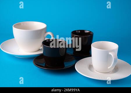 photo of two brown cups and saucers with two white cups and saucers on a blue background Stock Photo