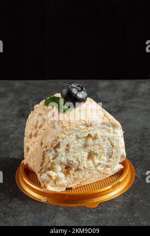 Meringue roll cake with cream on dark background. delicious dessert on the pastry shop menu. Close up Stock Photo
